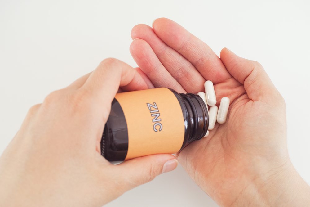 Person taking Zinc pills out of a bottle. Close up.
