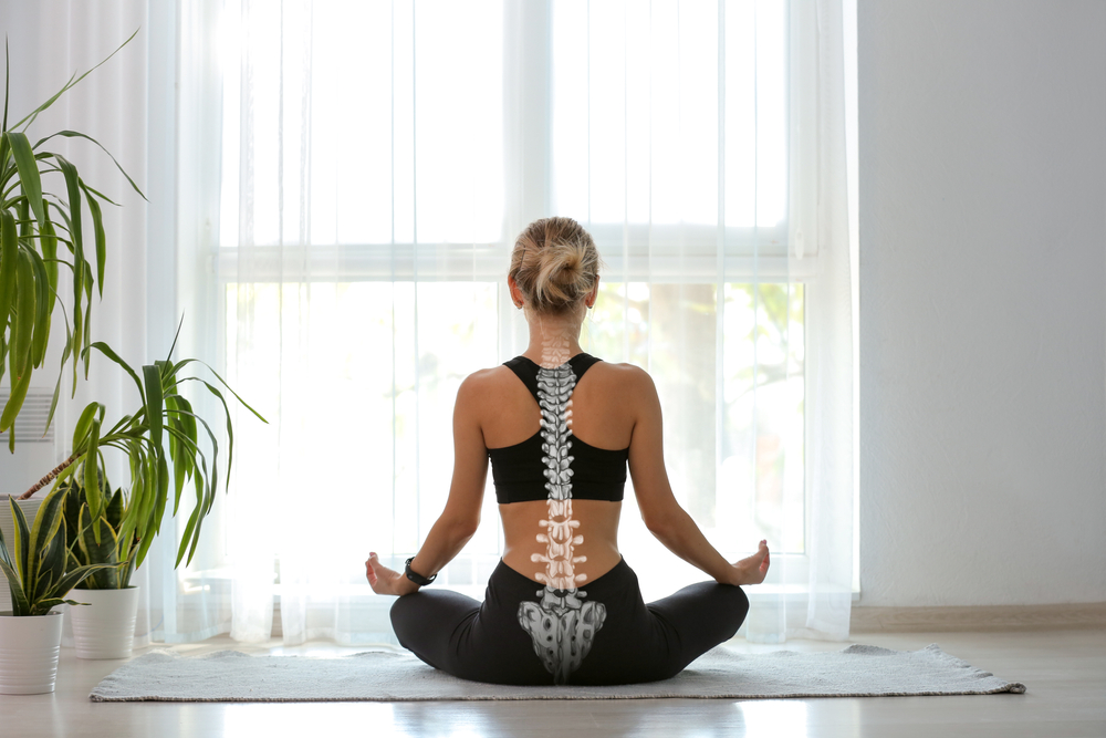 Young woman with good posture meditating at home, back view