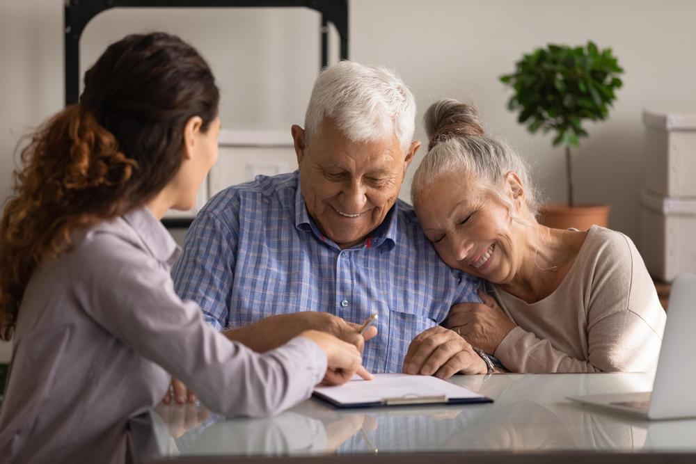 Reaching an agreement. Happy old spouses visiting lawyer broker realtor to buy real estate sign insurance policy create will. Excited aged married couple clients sign financial deal with bank manager