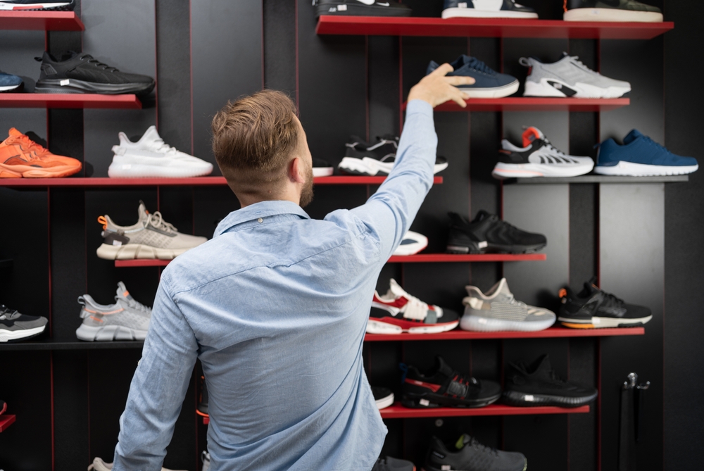 young man picking a sporty shoes in the shop, new sneakers in sports store for men, mens shopping sports shoes