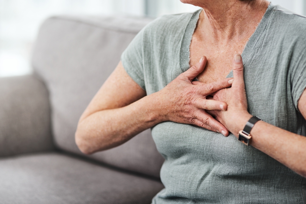 Heart attack, chest pain and sick senior woman with asthma in her home living room or couch with an emergency. Crisis, medical and elderly person with discomfort due to illness or breathing problem