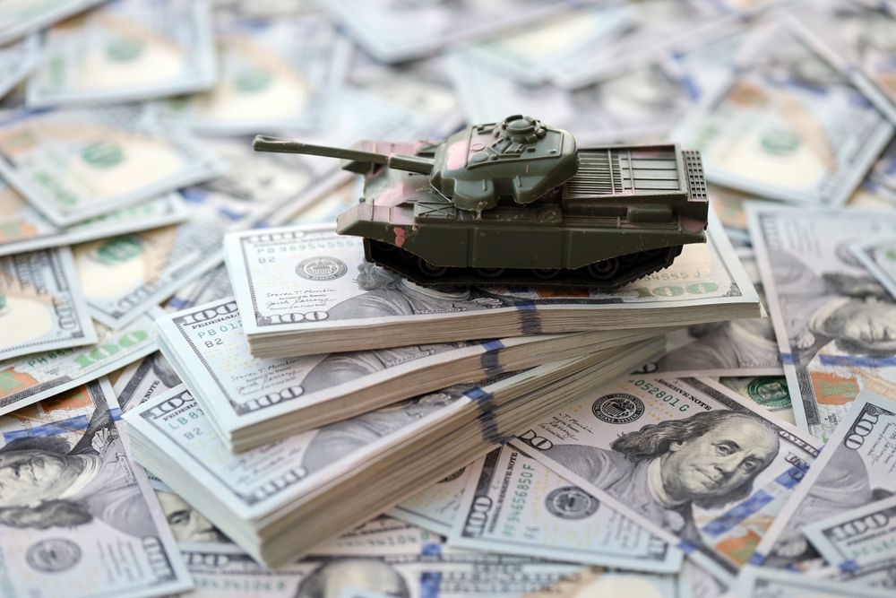 Toy tank on US hundred dollar bills banknotes close up. The concept of war costs, military spending and economic crisis