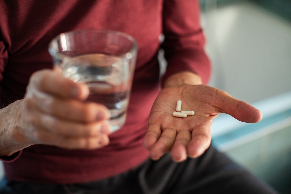Elderly man taking medication in bathroom