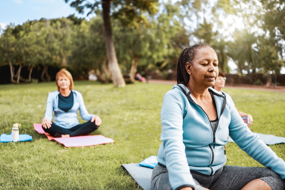 Multiracial senior sports people relax in yoga meditation practice at City Nature. Health care, older community concept