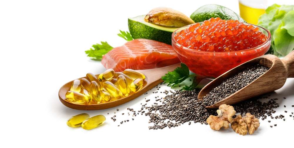 Diet and omega 3 nutritional supplements concept of fish oil capsules in wooden spoon and food rich in omega 3 fatty acids on white background..
