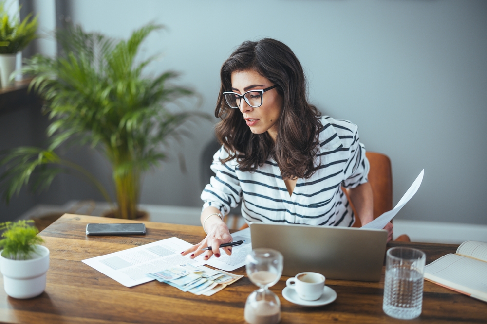 A smart business woman who keeps a paper account using a calculator, an old woman manages the account's finances, calculates the tax on the cash budget, plans to pay off a bank loan debt