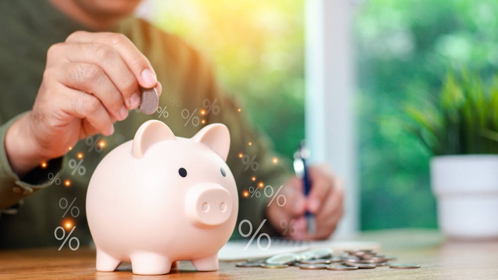Concepts of saving money and financial planning. Man hand holding piggy bank on wood table, income, return, retirement, compensation fund, investment, dividend tax, stock market