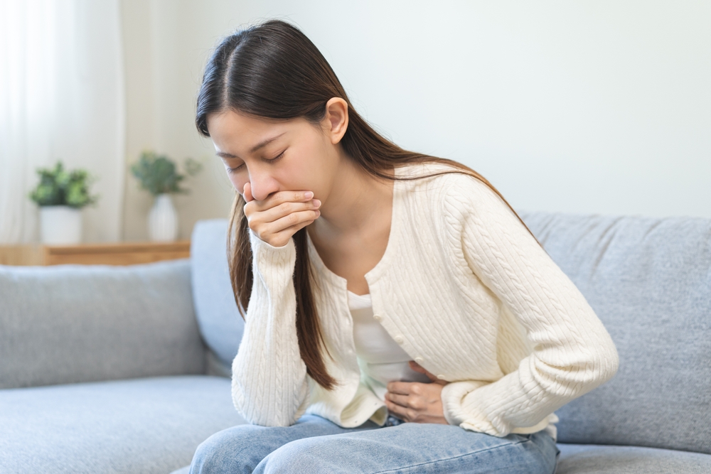 Unhappy pregnant asian young woman, pain girl suffering from nausea, having vomit feeling sick covering mouth, touching belly having problem throwing up from food poisoning, lady with morning sickness