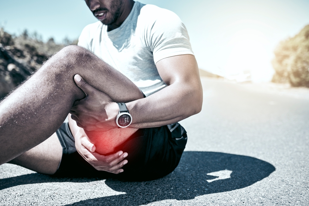 Hamstring pain, hands and person with injury on road after training accident, cramp or exercise risk. Legs, fitness and runner with muscle inflammation, thigh massage or problem with red glow outdoor
