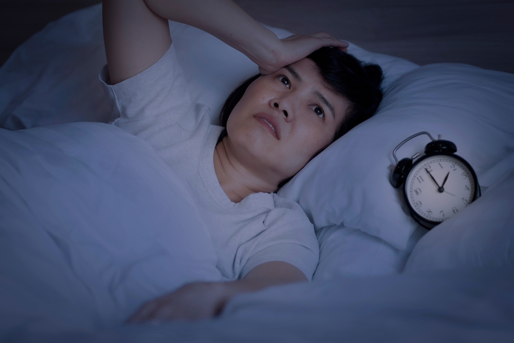 Insomnia in middle-aged women. An Asian woman tries to sleep but she cannot sleep because she has anxiety and stress from work. This symptom should be seen by a doctor for treatment.