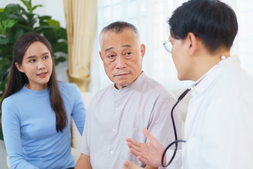 Senior Asian man having an annual health check by doctor. A male doctor comes to see a senior adult patient at home and checks his heart health and blood pressure. Doctor visiting elder patient's home
