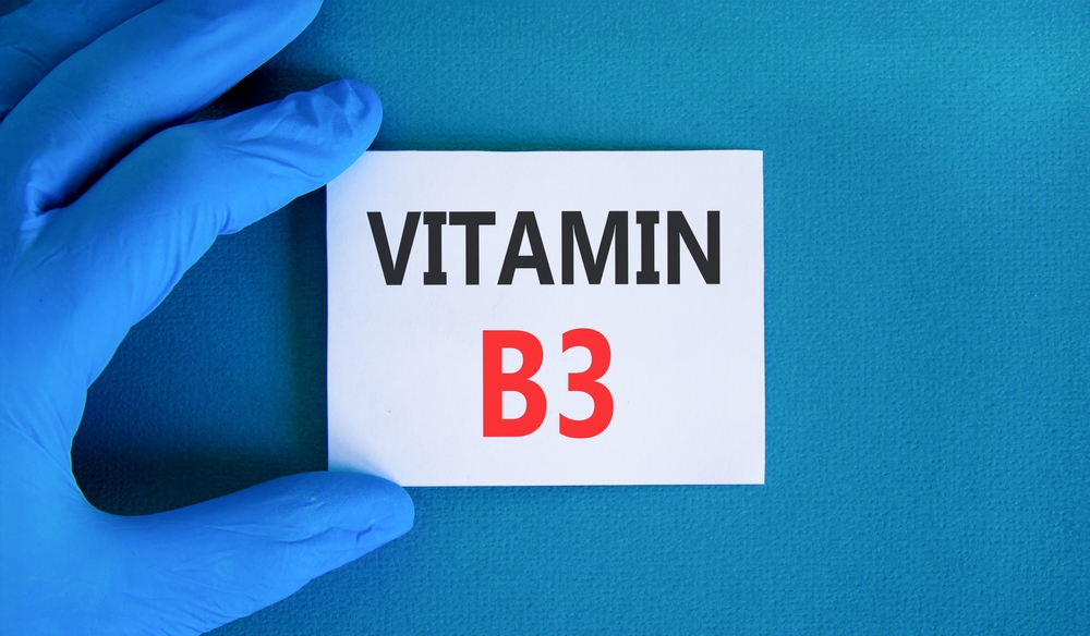 Vitamin B3 niacin symbol. Concept words Vitamin B3 on beautiful white card. Doctor's hand in blue medical glove. Beautiful blue background. Medical healthy lifestyle Vitamin B3 niacin concept.