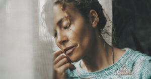 woman with eyes closed leaning against wall