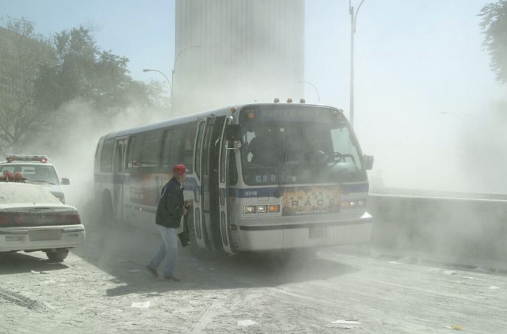 city bus sits in the middle of the street, nearly hidden by the thick clouds of ash