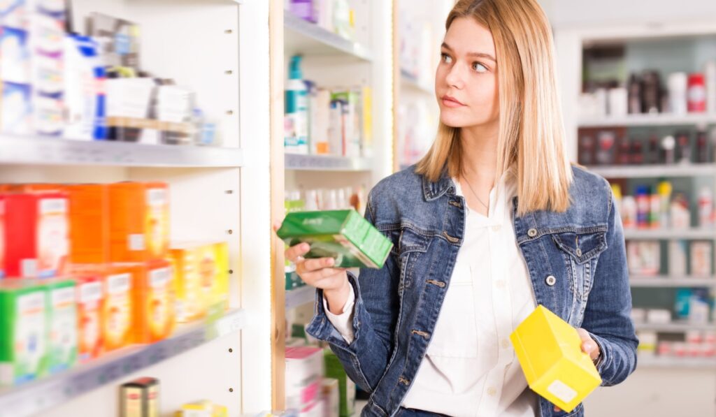 Pretty satisfied woman shopping health supplements in drugstore
