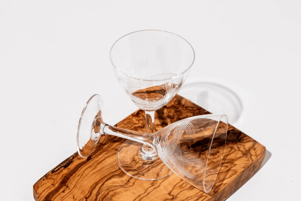 Thin tall beverage glasses on a wooden cutboard