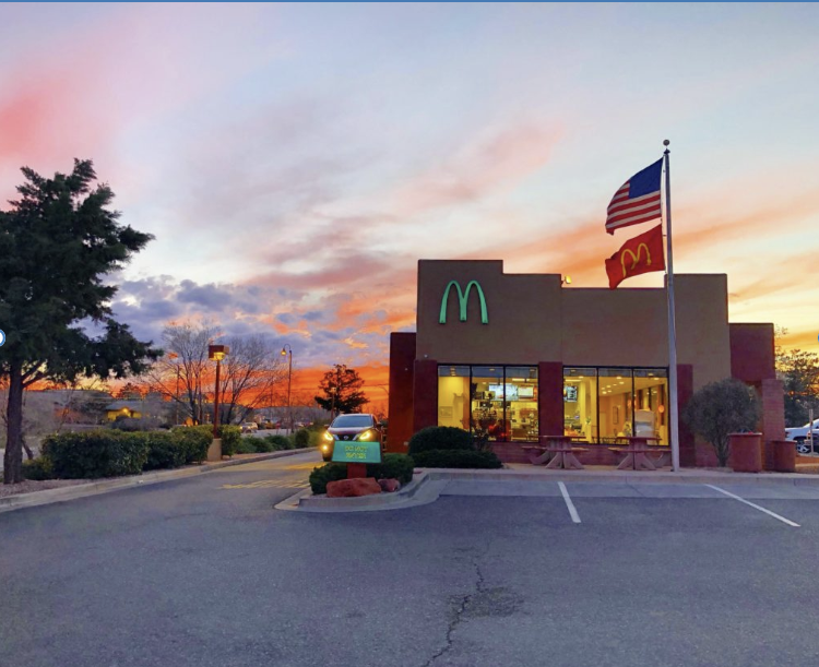 McDonald's drive thru with turquoise McDonald's arches, American flag and traditional McDonald's flag.