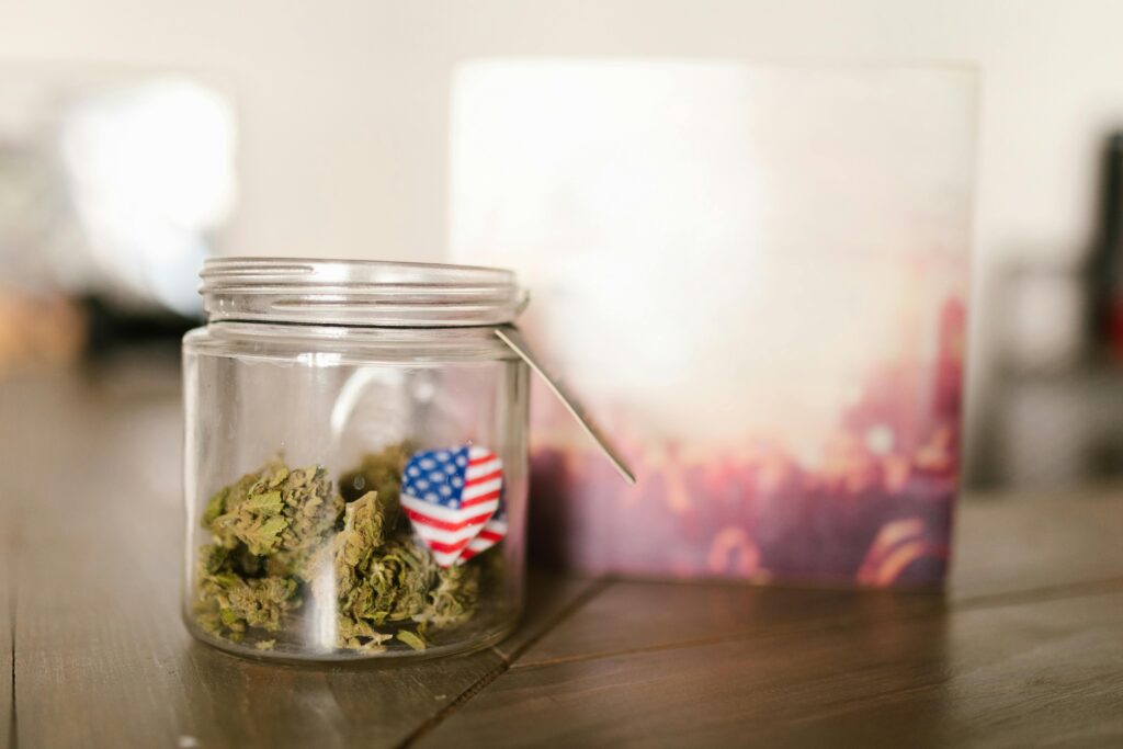 Marijuana buds in glass jar with US flag representing federal regulations.
