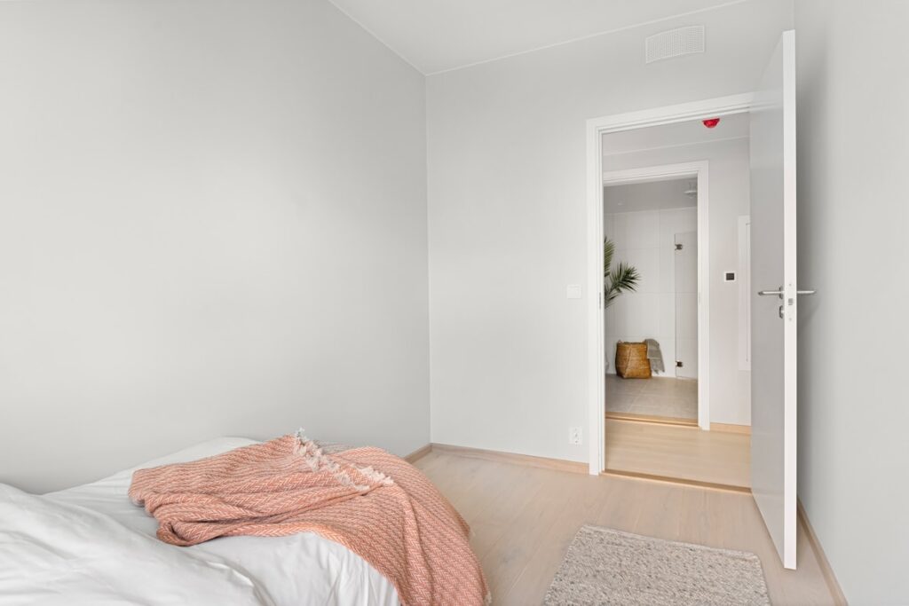Bedroom seen through a doorway with the bed's foot pointing toward the door.