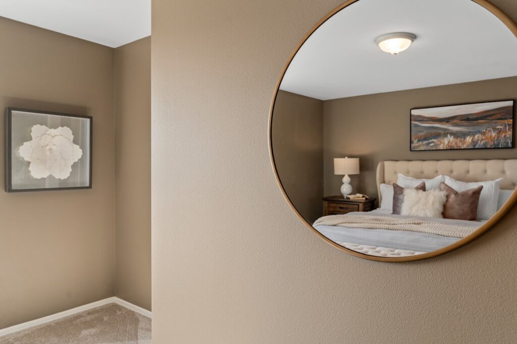 Large round mirror that shows the bed's reflection in the bedroom.