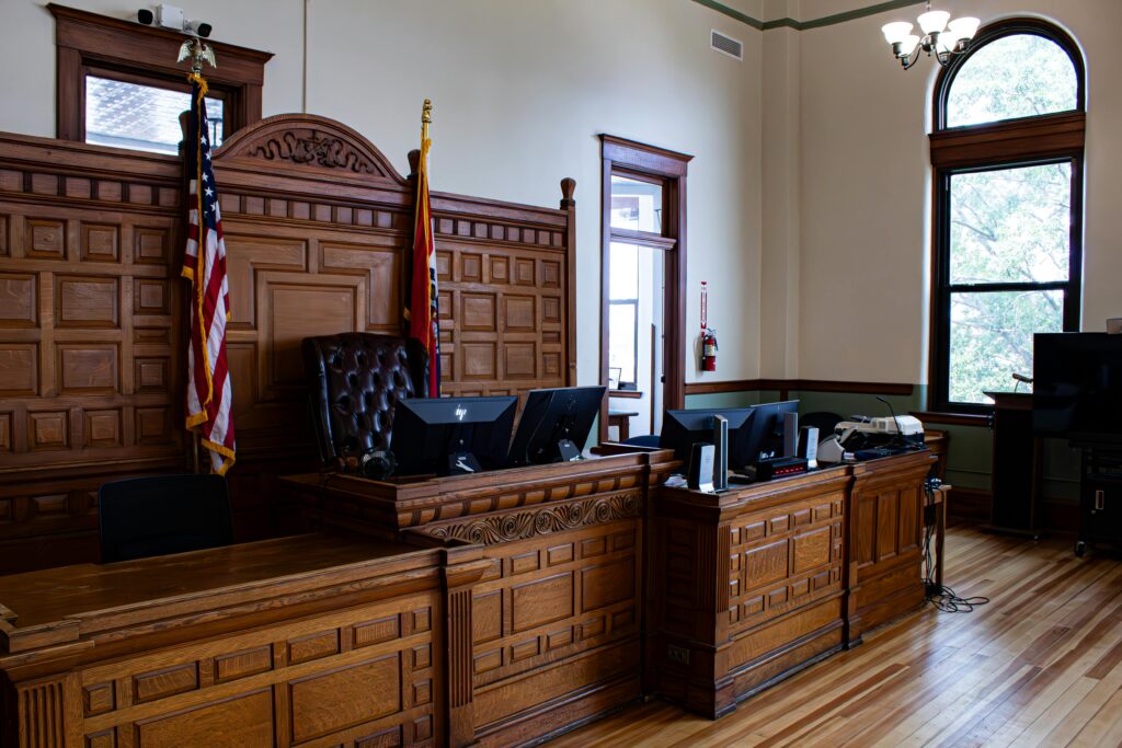 Courtroom with wooden judge's bench, American flag, and formal legal setting.