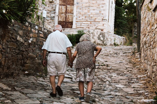 elderly couple walking up a cobble road