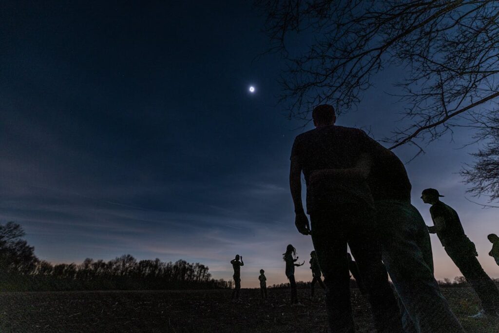 Wide Angle Shot of People Standing on a Field at Night

