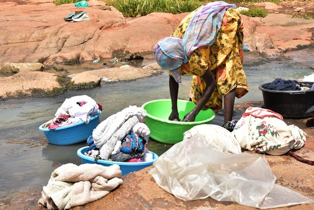 African cleaning clothing by the river