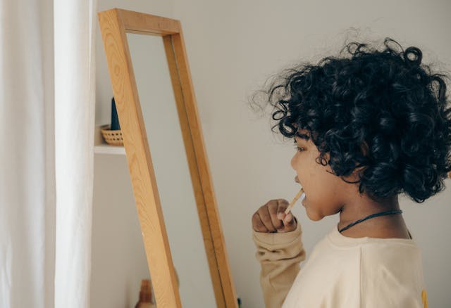 child brushing his teeth in front of a mirror