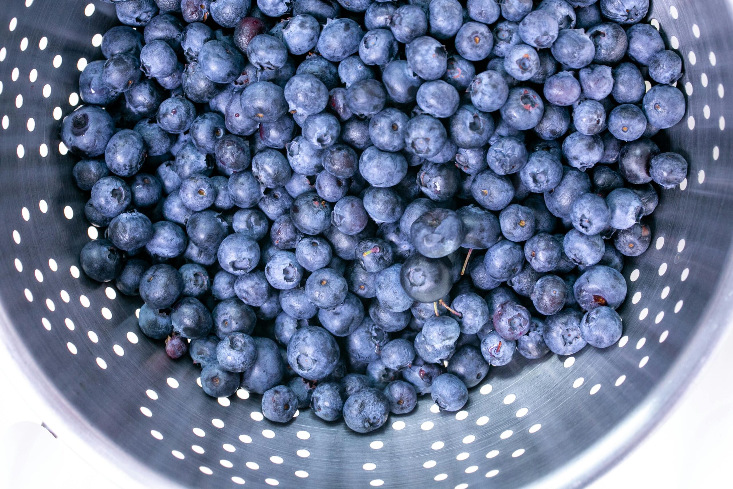 blueberries in metal colander being washed