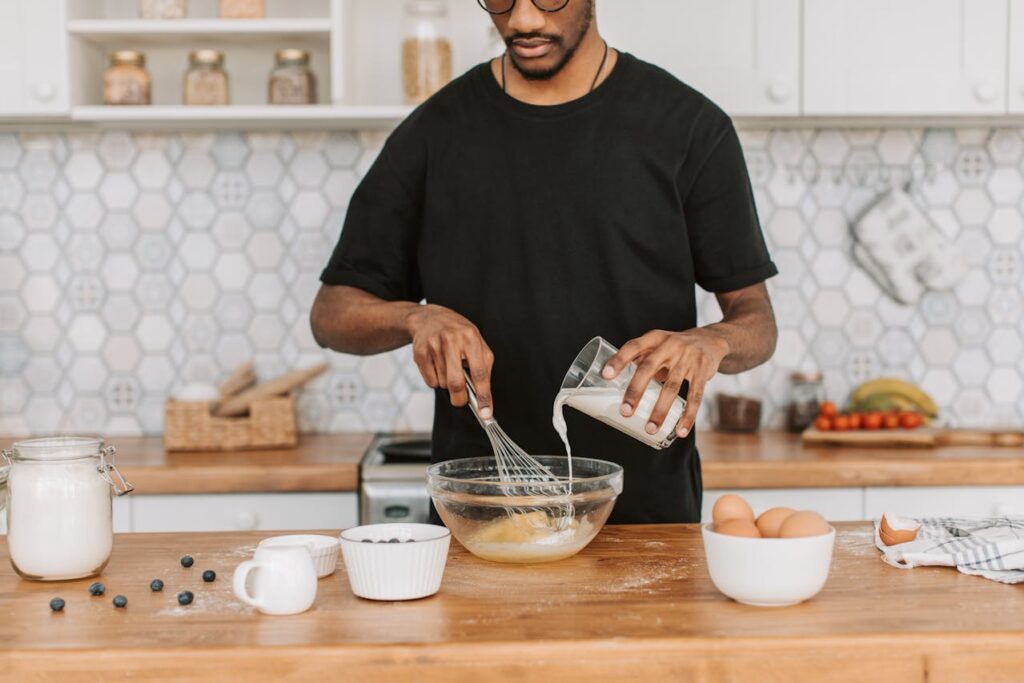 A Man in a Black Shirt Pouring Milk on a Bowl
