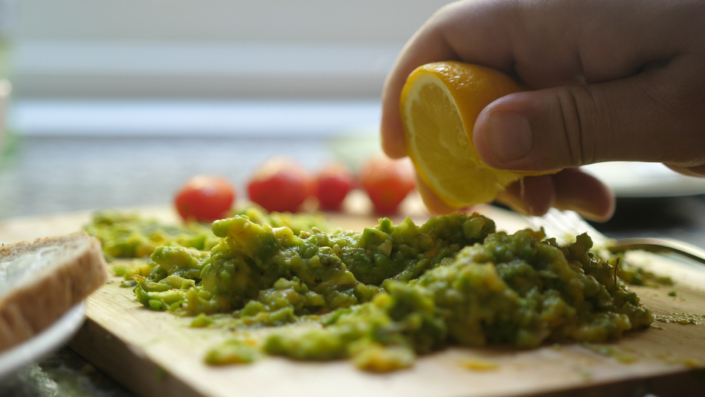 Close up Of Hand Squeezes Lemon Juice Over Avocado Toast. Breakfast Time, Healthy Food.