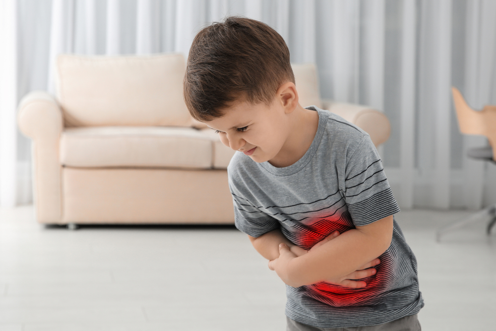 Little boy suffering from stomach pain in living room
