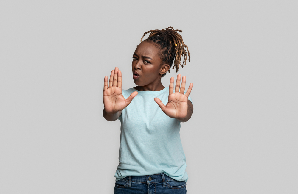 Indignant young black woman showing no gesture with both hands, grey background
