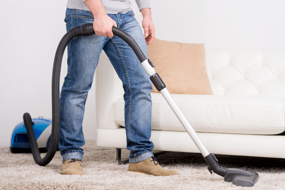 Vacuum Cleaner. A man does house work with a vacuum cleaner
