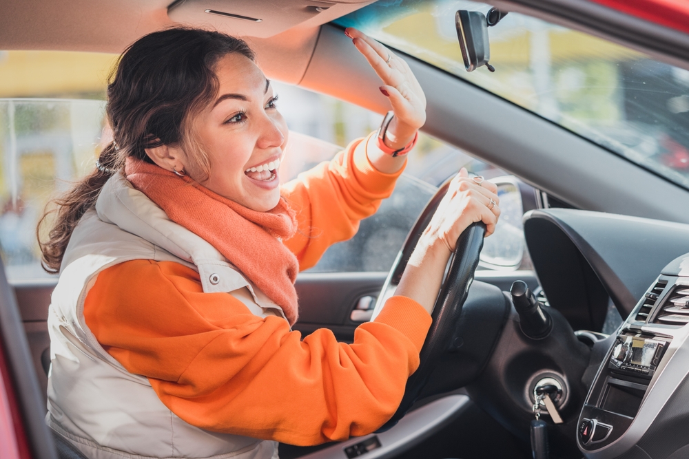 Polite woman driver raised her hand as a sign of respect and says thank you for giving way. Relations between people in traffic regulations