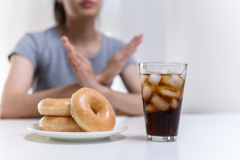 Dieting or good health concept. Young woman rejecting Junk food or unhealthy food such donut sweets or soda drink and choosing healthy food such as fresh fruit or vegetable.
