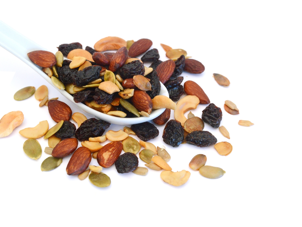 Mix nuts, dry fruits and grapes in spoon on a white background