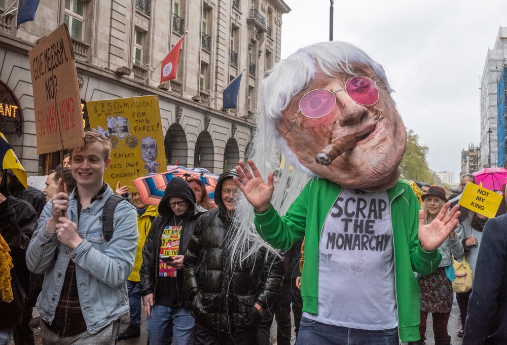London  UK - May 6 2023: A man wearing a huge Jimmy Savile mask and a T-shirt stating "Scrap the Monarchy" marches with anti-monarchy and republican protestors in Piccadilly on coronation day