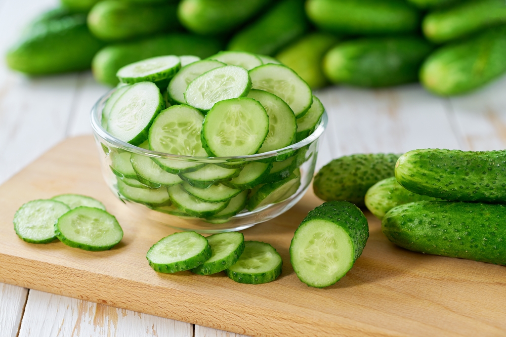chopped organic cucumbers slices in a clear glass bowl on a light table. Fresh cucumbers.