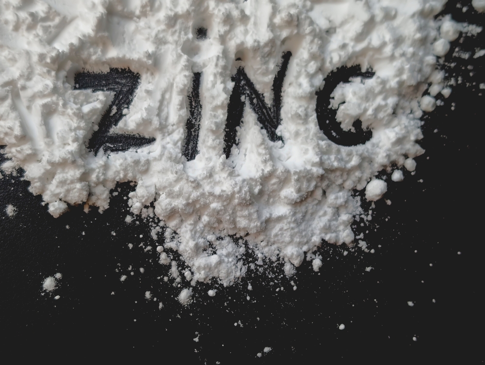 White powder on a black background. Letters zinc. Mineral zinc. Bio hacking concept. Copy space