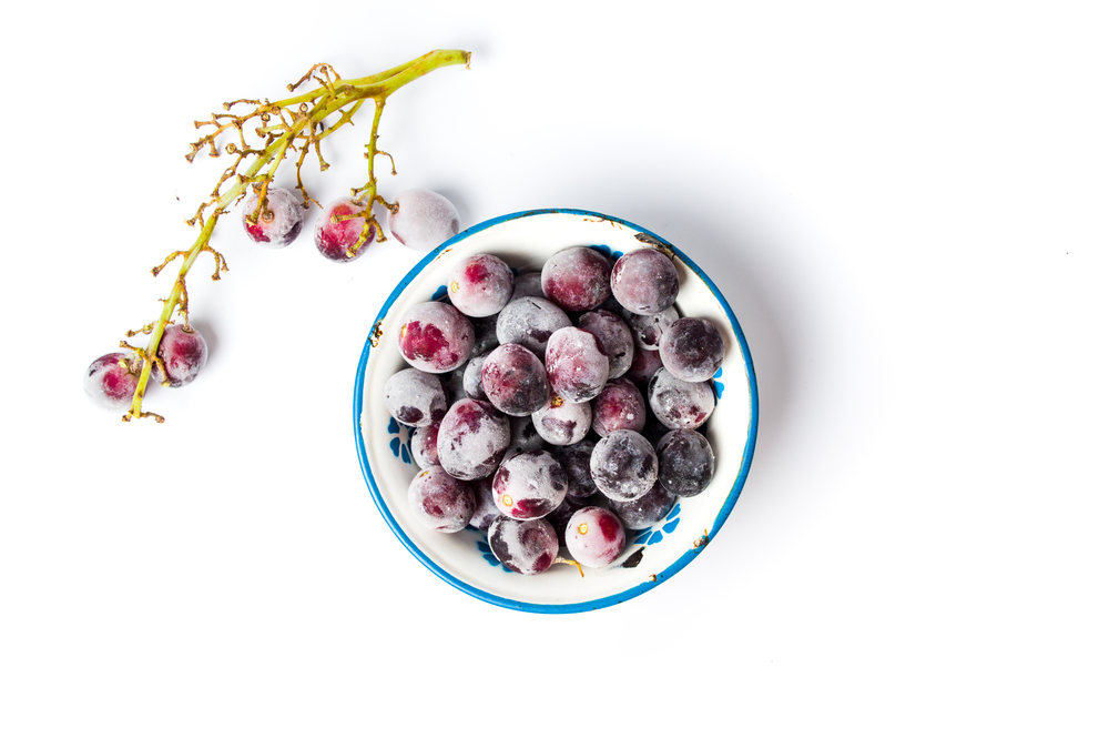 Frozen grapes cluster with ice on white background