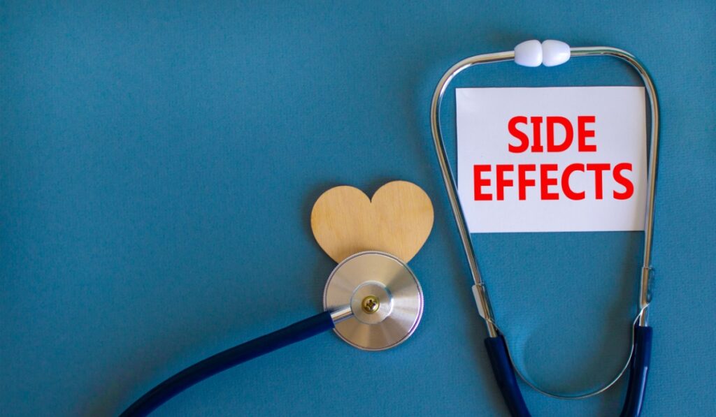 Side effects symbol. White card with words Side effects, beautiful blue background, wooden heart and stethoscope. Medical and side effects concep