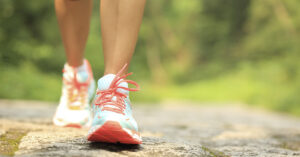 close up of person wearing running shoes walking on stone path