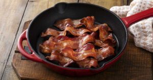bacon strips cooking in frying pan