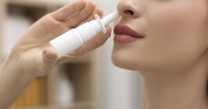 Could Your Allergy Nasal Spray Double as a COVID Shield? woman taking a nasal spray