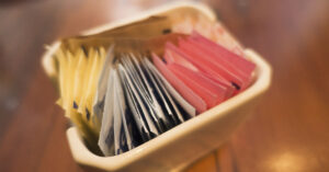 Packets of artificial sweeteners in a small porcelain dish