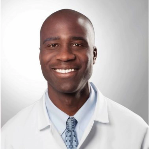 Florida Surgeon General Joseph Ladapo wearing a white medical coat and blue tie, smiling at the camera.
