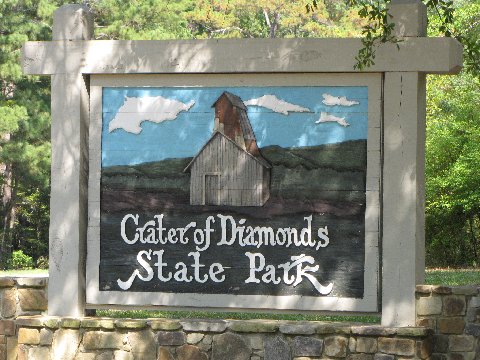 Crater of Diamonds State Park entrance sign with painted barn and rolling hills.