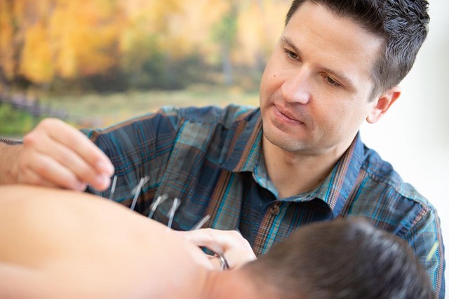man performing acupuncture on patient